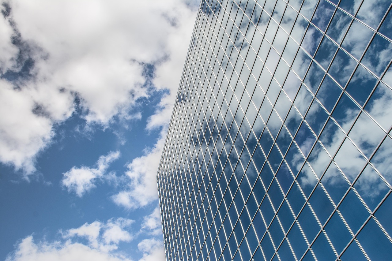 Edificio de vidrio reflejando el cielo y las nubes